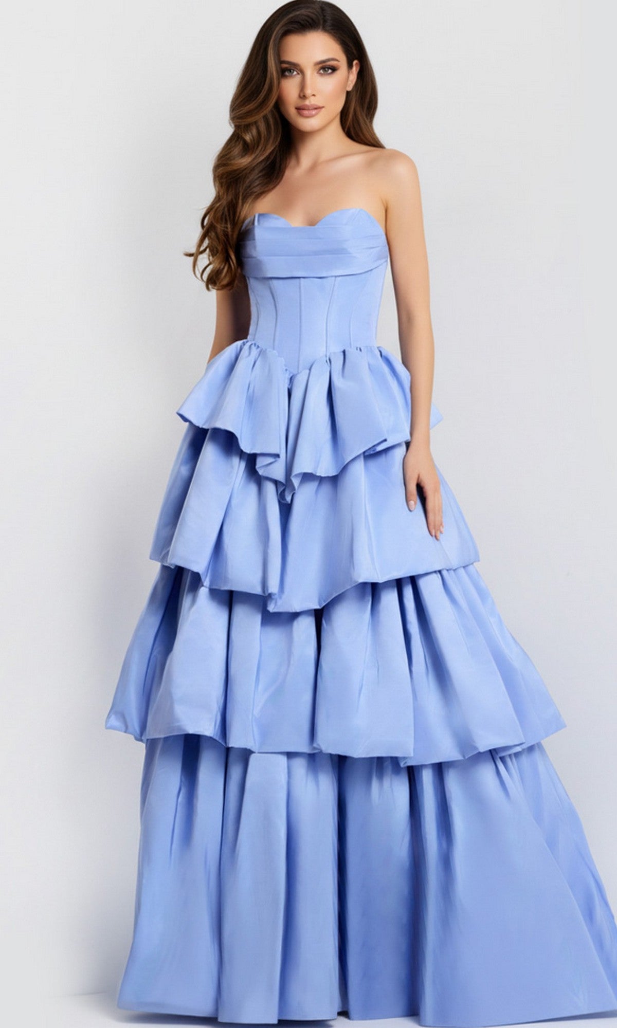 A woman poses against a plain background in the Jovani 45111 Strapless Ruffle Long Prom Ball Gown, a periwinkle floor-length dress with a fitted bodice and layered, tiered ruffled skirt.
